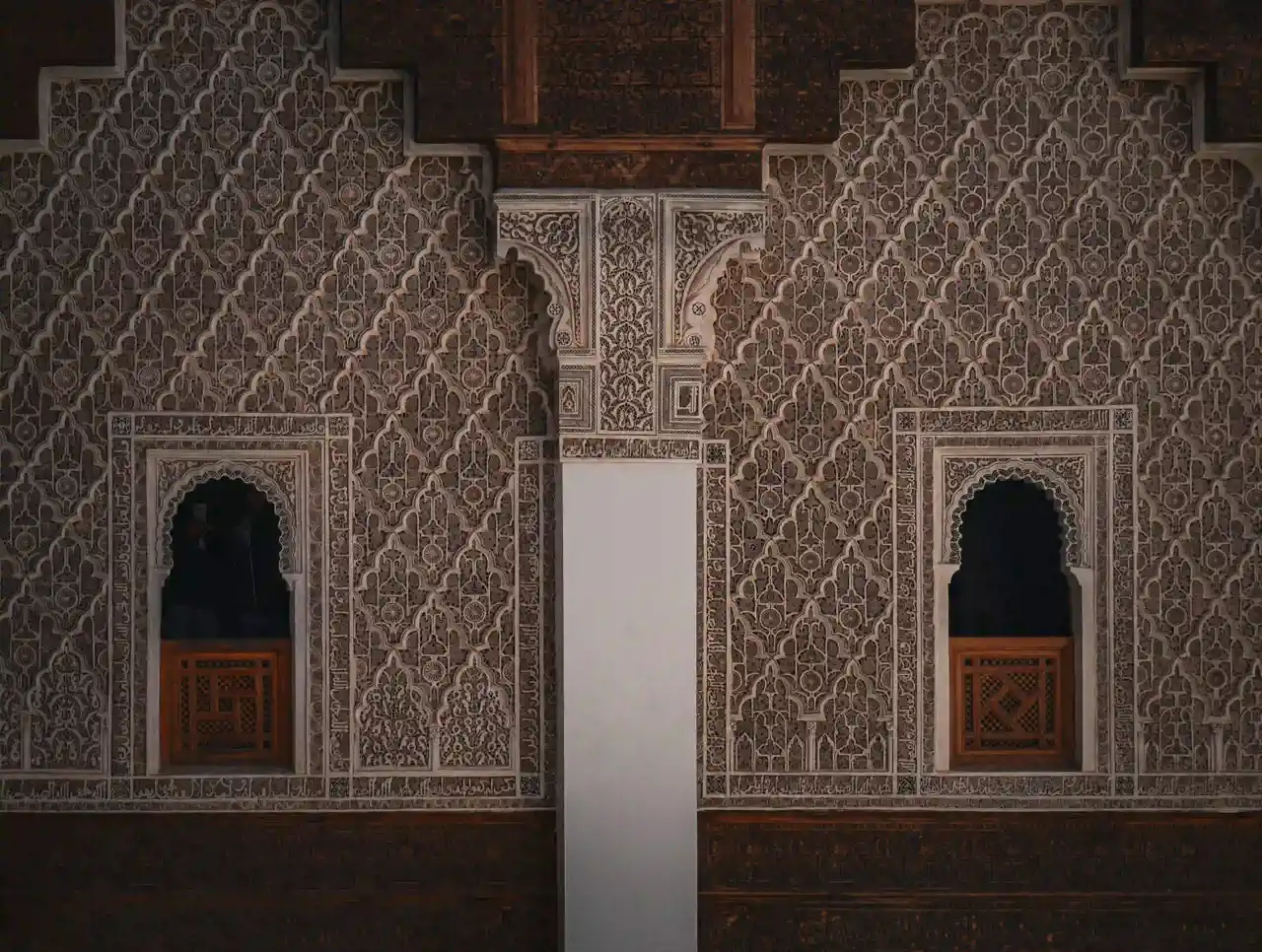 Intricately carved stucco and zellige tilework on the walls of a historic Marrakech madrasa, Morocco