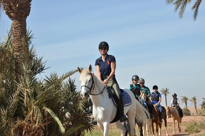 Group of riders on horseback along a palm-lined trail near Marrakech