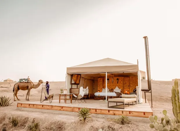 Open luxury tent with a bed and lounge deck in the Agafay desert