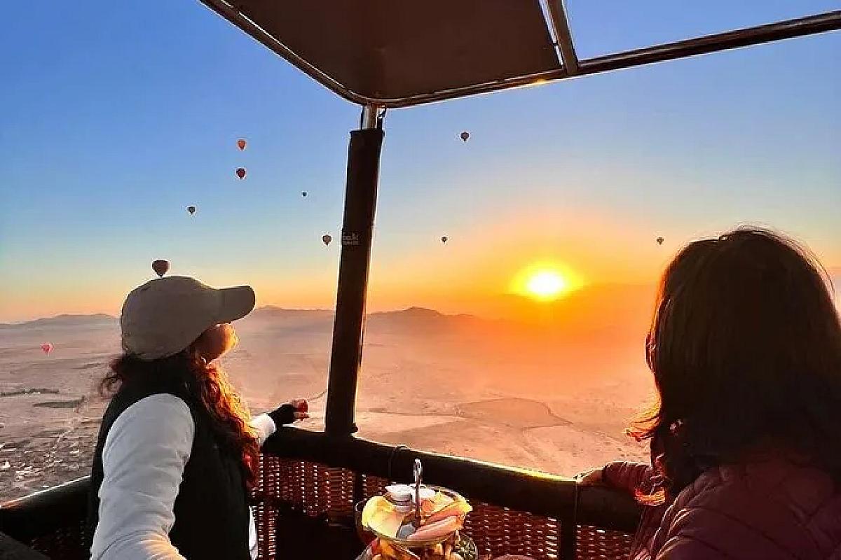 Passengers watching sunrise from a hot air balloon basket near Marrakech