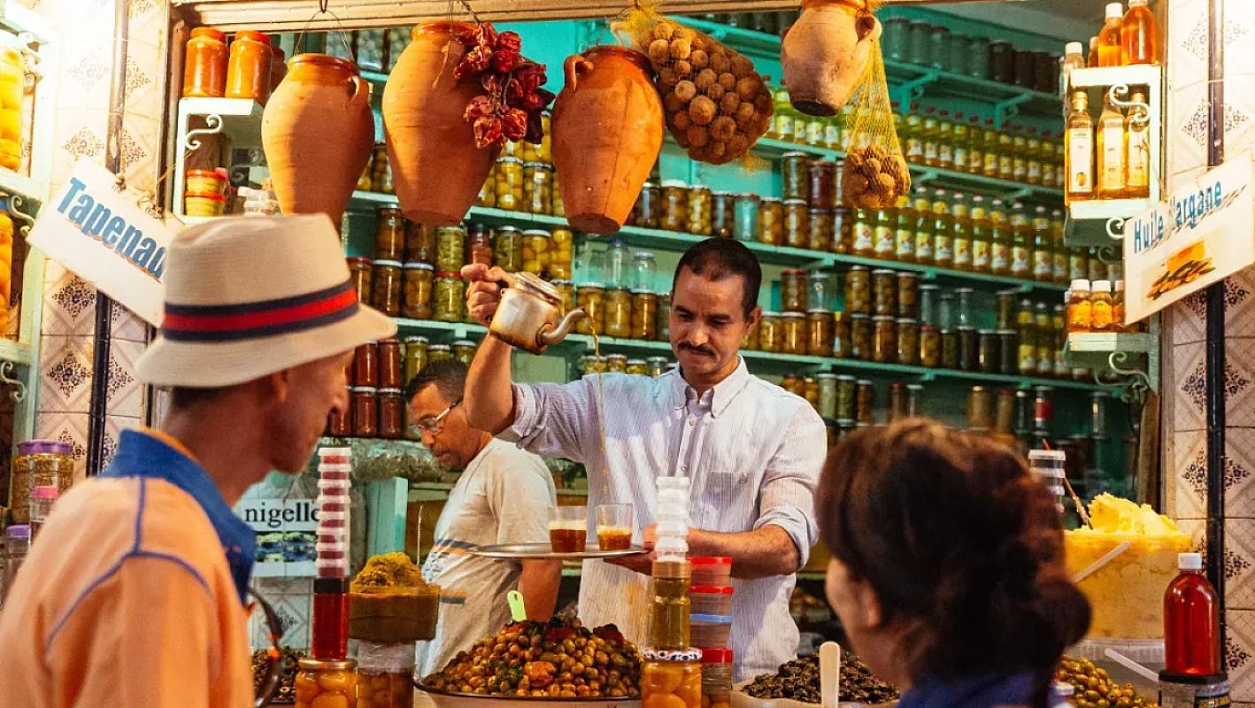 Vendor serving olives and preserves at a Marrakech market stall