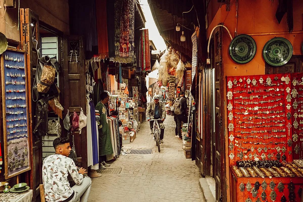 Shoppers passing craft stalls in a narrow Marrakech souk lane