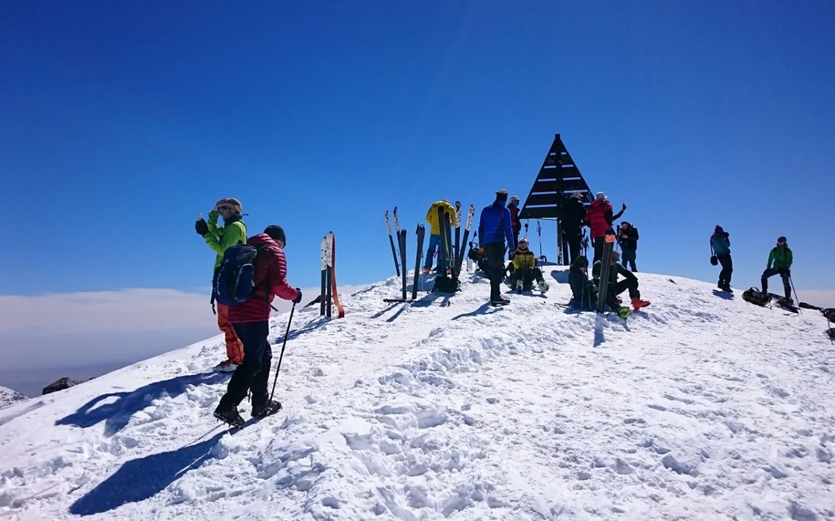 Trekkers gathered at the snow-covered summit marker of Mount Toubkal