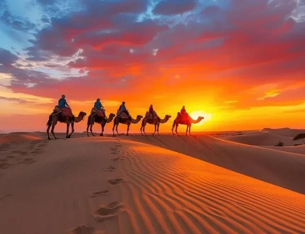 Camel riders silhouetted against a vivid desert sunset