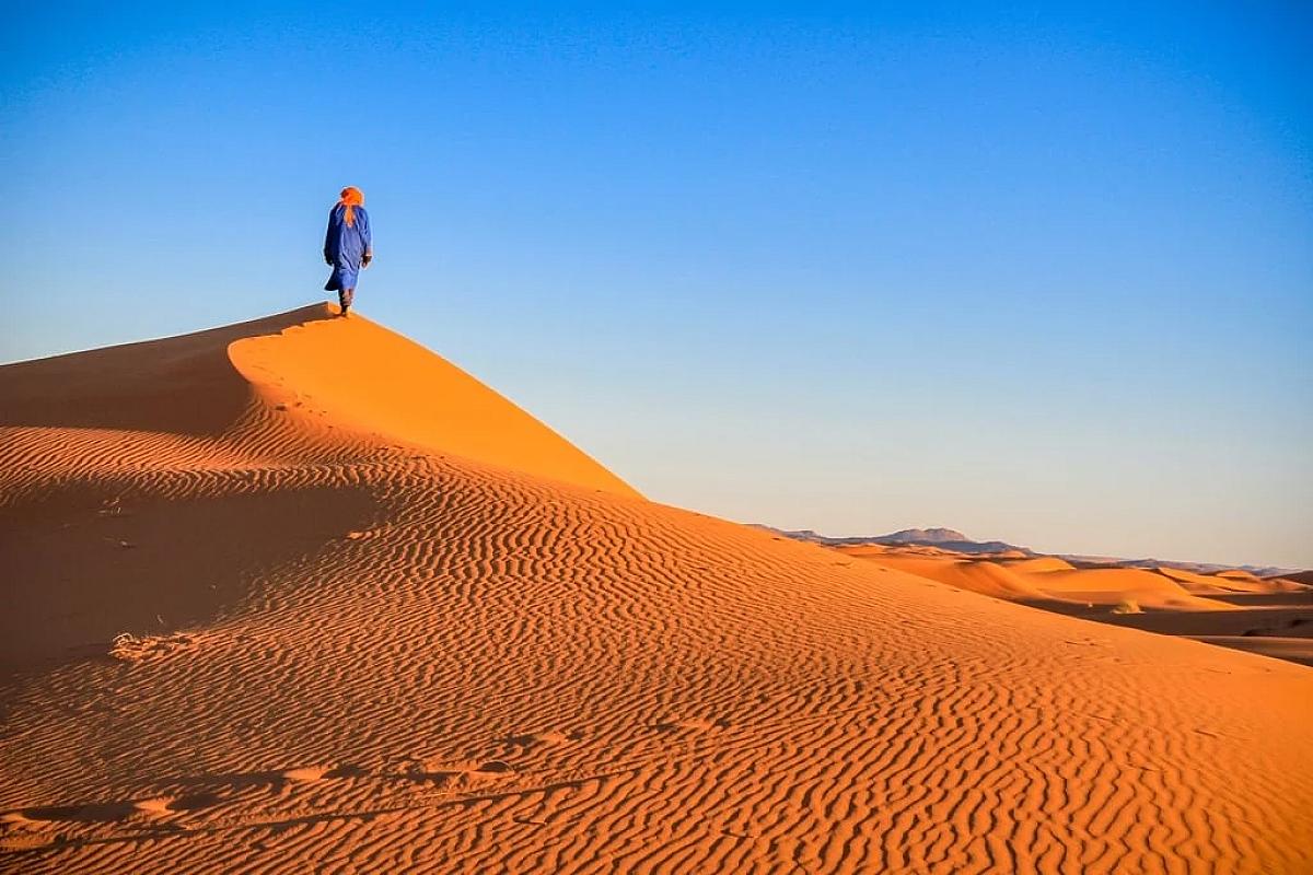 Blue-robed guide standing on a rippled Erg Chebbi dune
