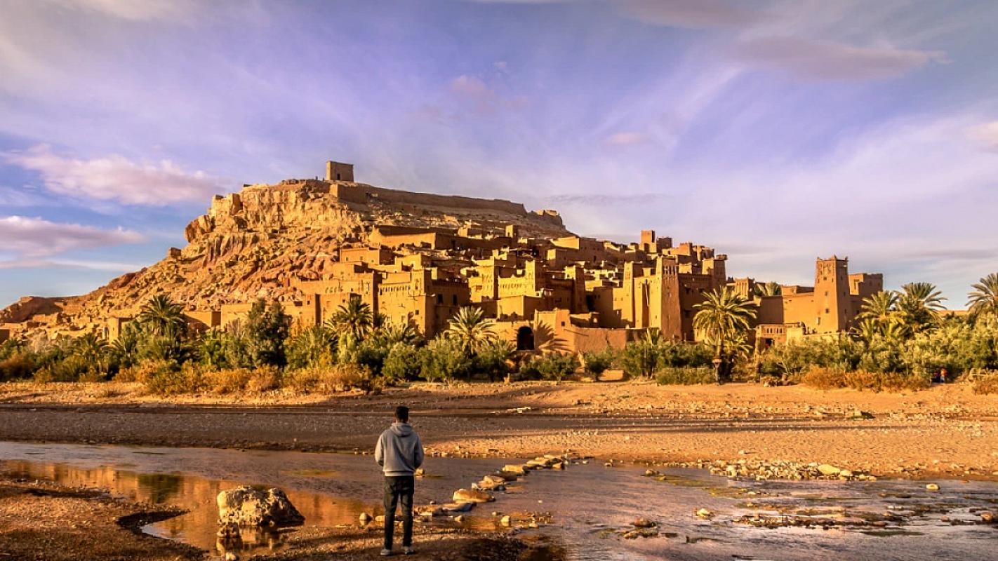 Traveller facing the Ait Benhaddou ksar across the riverbed