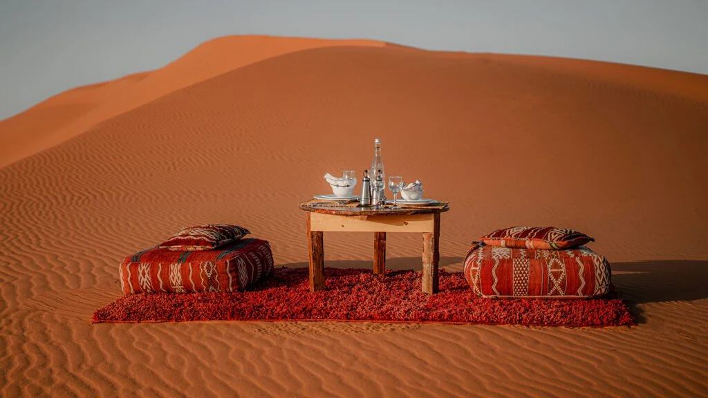 Tea table and cushions arranged on the golden Sahara dunes