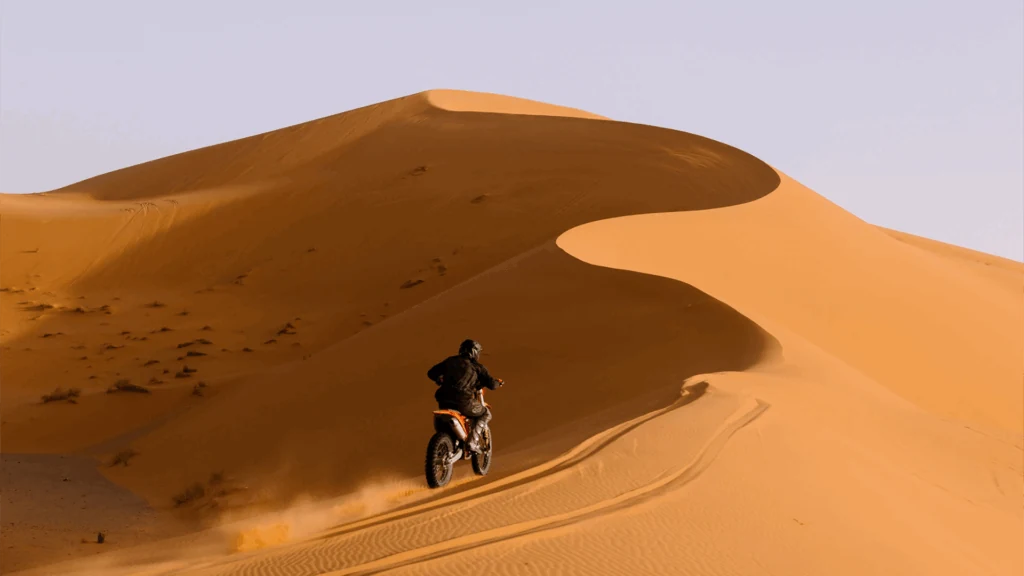 Motorbike climbing a tall sand dune near Merzouga