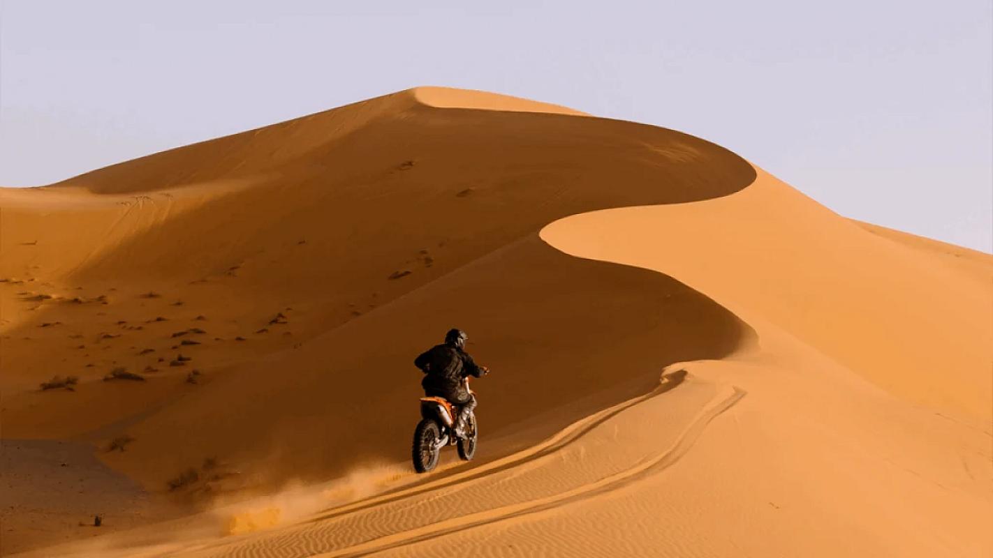 Motorbike climbing a tall sand dune near Merzouga