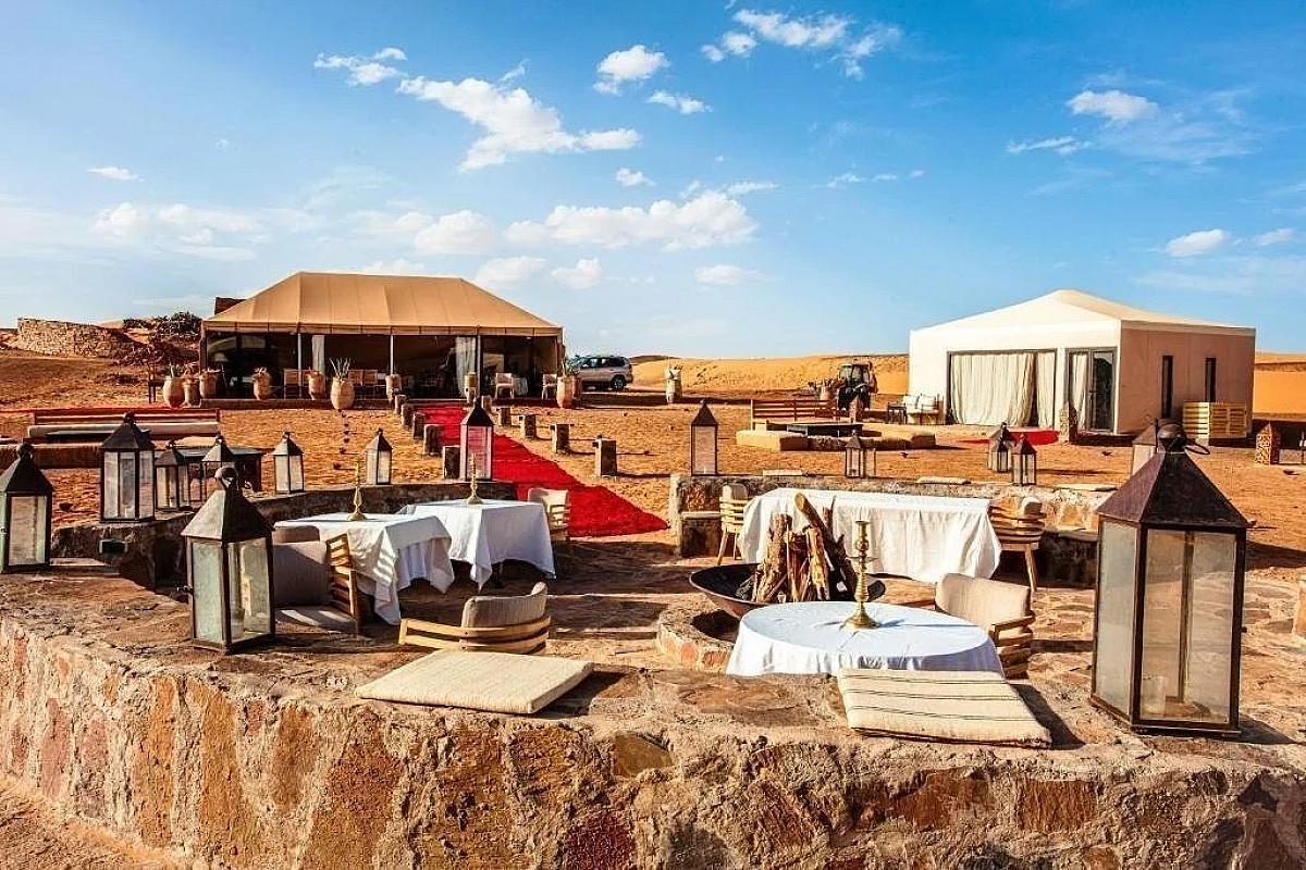 Lantern-lit dining tables at a desert camp among the dunes
