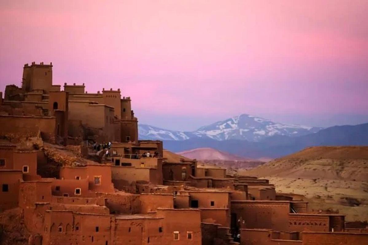 Kasbah village at dusk with snow-capped Atlas peaks behind