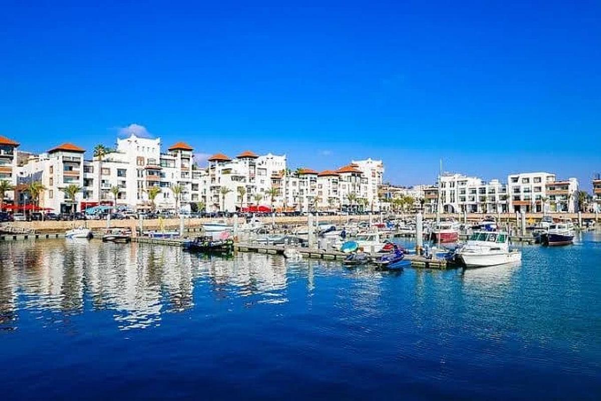 Boats moored in the Agadir marina beneath white apartment buildings